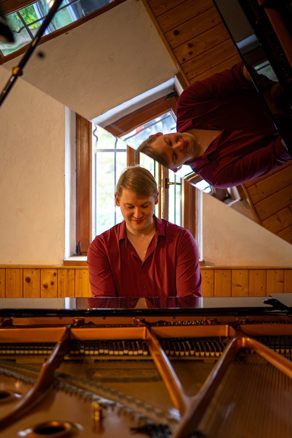 Johann Putensen am Flügel, gespiegelt im Instrument